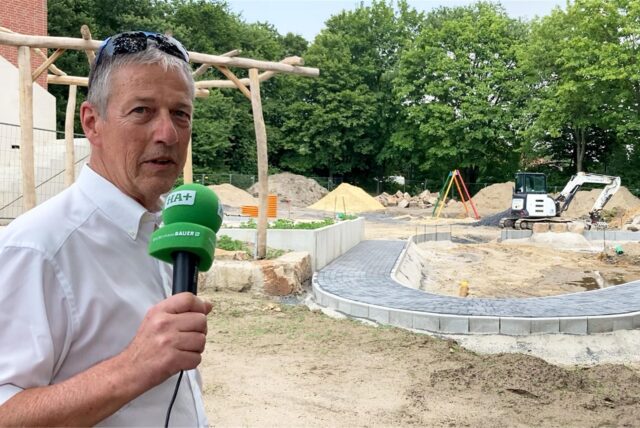 Michael Vaupel steht mit einem Mikrofon in der Hand auf dem Außengeländer des neuen Kindergartens in Herten-Disteln.