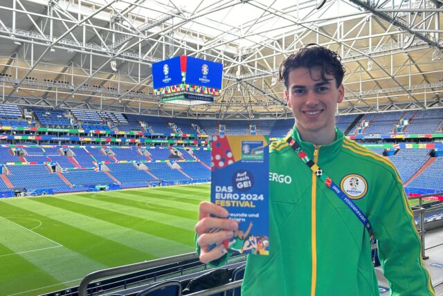 Roman Lachowicz in der Arena Auf Schalke mit einem Flyer für das EURO 2024 Festival in Gelsenkirchen.