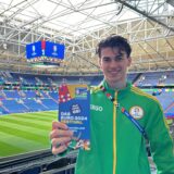 Roman Lachowicz in der Arena Auf Schalke mit einem Flyer für das EURO 2024 Festival in Gelsenkirchen.