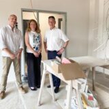 Sebastian Scholz (Hertener Immobilienbetrieb), Kirsten Wietoska (Jugendamt Stadt Herten) und Michael Vaupel (Vorstandsvorsitzender des DRK-Kreisverbandes Recklinghausen) stehen in der neuen Kita in Disteln, in dem Handwerker noch einige Arbeiten verrichten müssen und einen kleines Arbeitstisch aufgebaut haben.