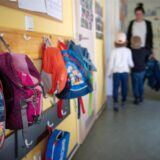 Innenansicht eines Kindergartenflurs, links im Bild hängen kleine Rucksäcke an Haken.