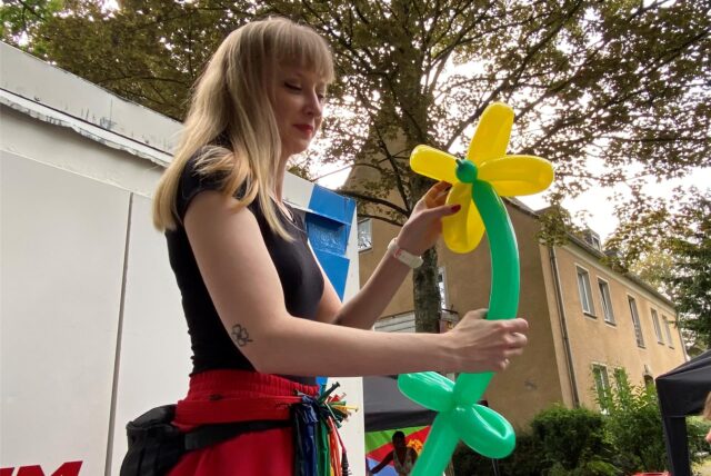 Stelzenläuferin „Phoenix Mia“ hat aus Luftballons eine Blume gestaltet.