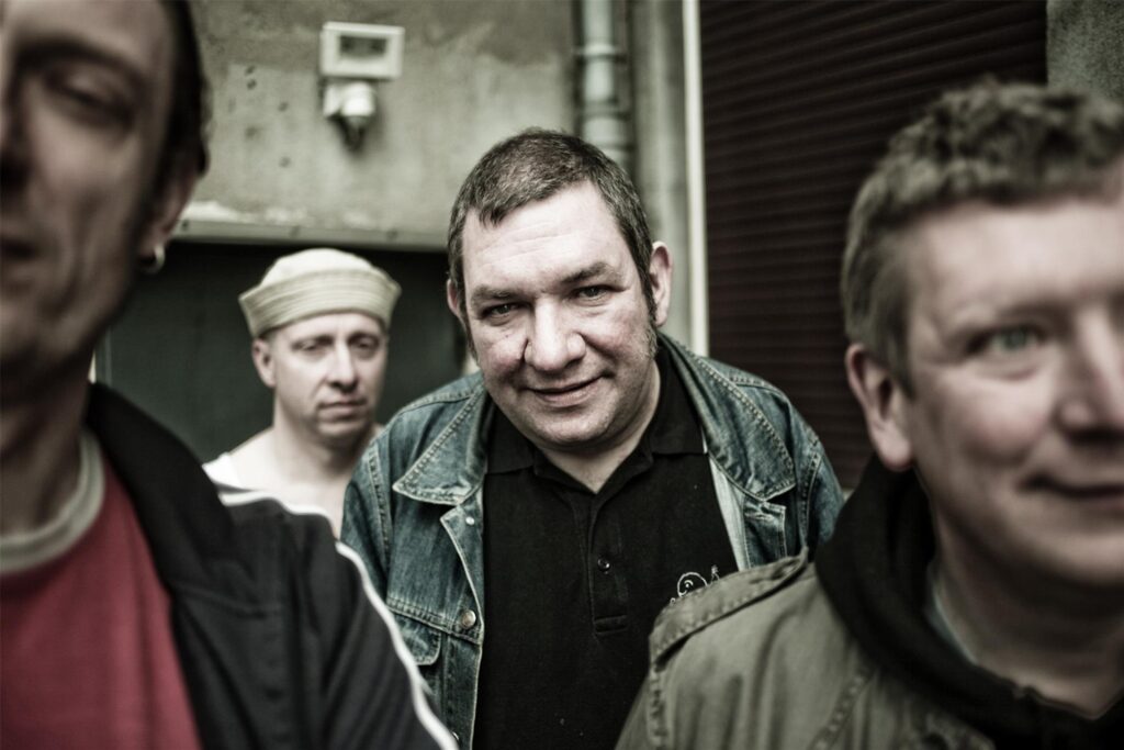 Der Frontsänger der Punkband die Kassierer guckt in die Kamera. Um ihn herum stehen seine Bandmitglieder. Der Frontsänger der Punkband die Kassierer guckt in die Kamera. Um ihn herum stehen seine Bandmitglieder.