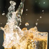 Apfelschorle spritzt aus einem Glas.