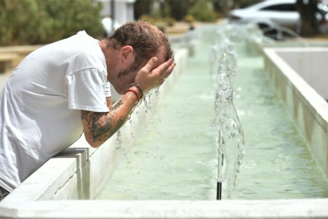 Ein Mann kühlt sich in einem Brunnen ab.