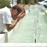 Ein Mann kühlt sich in einem Brunnen ab.