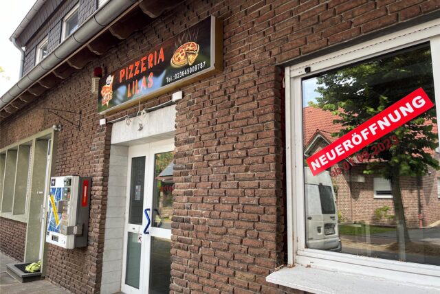 Ansicht einer Pizzeria mit Neueröffnungs-Schild im Fenster