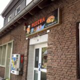 Ansicht einer Pizzeria mit Neueröffnungs-Schild im Fenster