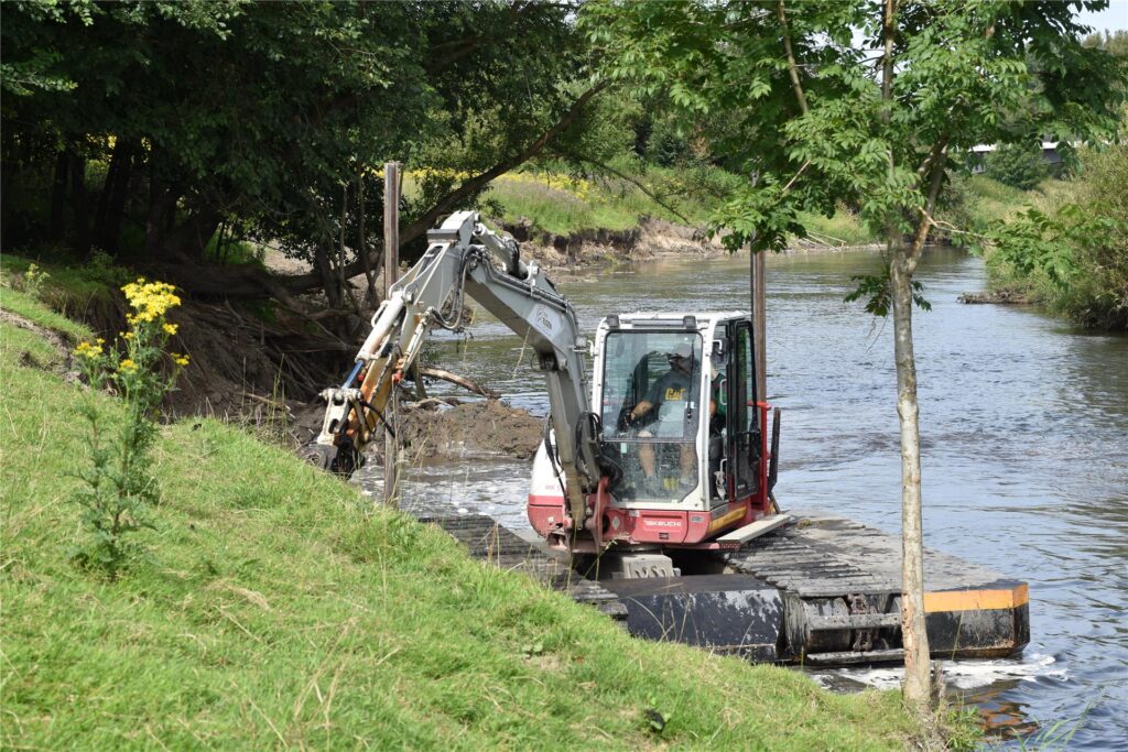 Ein Schwimmbagger gräbt auf der Lippe am Ufer.
