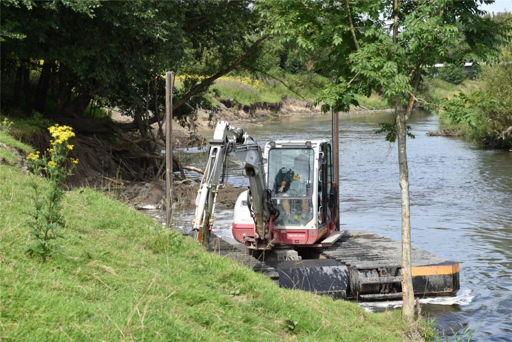 Ein Schwimmbagger gräbt auf der Lippe am Ufer.