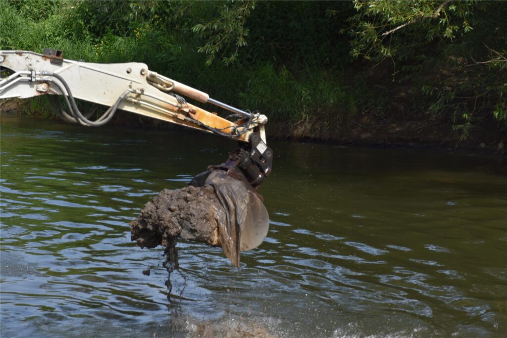 Ein Schwimmbagger gräbt auf der Lippe am Ufer.