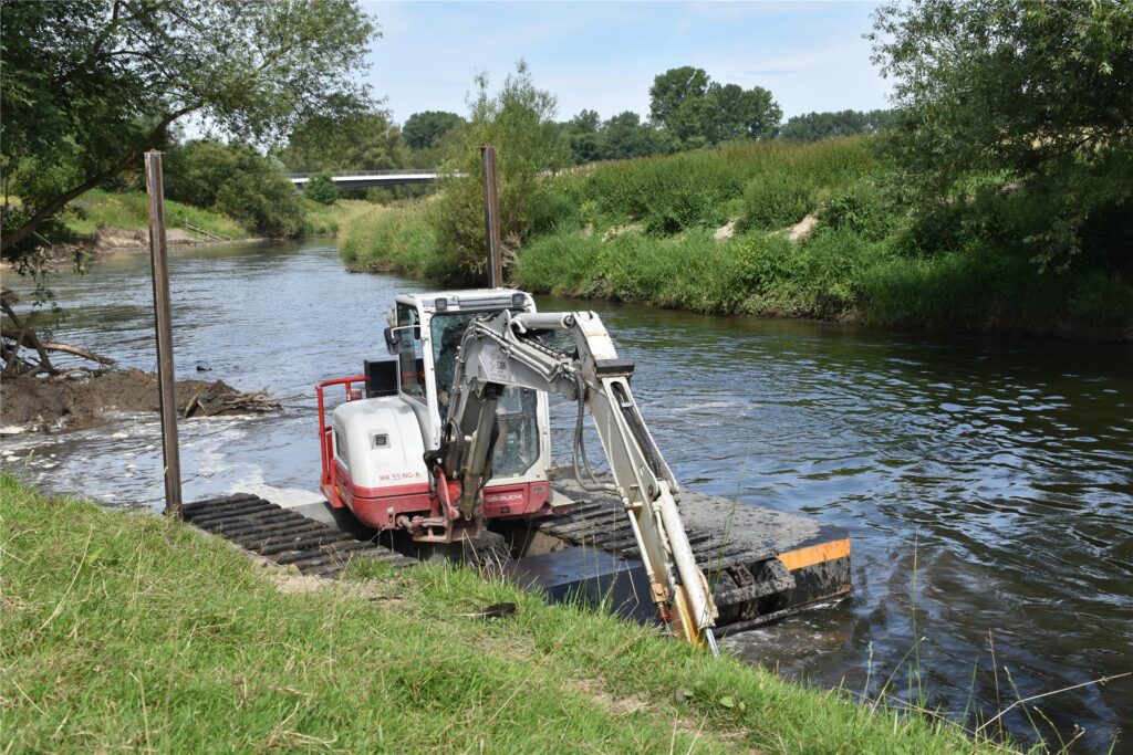 Ein Schwimmbagger gräbt auf der Lippe am Ufer.