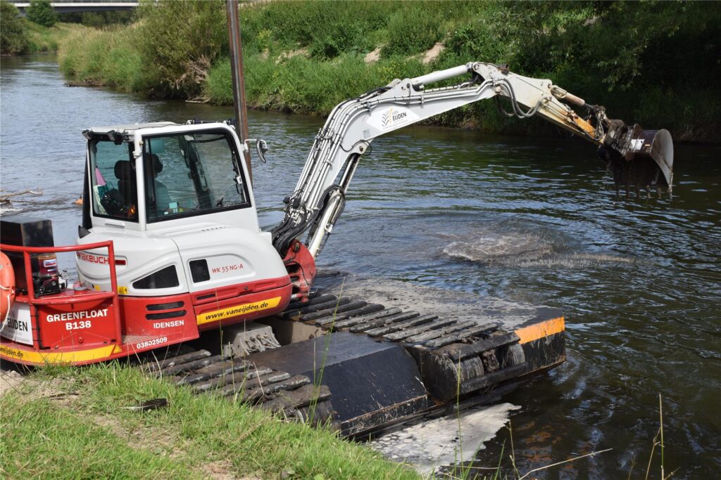 Ein Schwimmbagger gräbt auf der Lippe am Ufer.