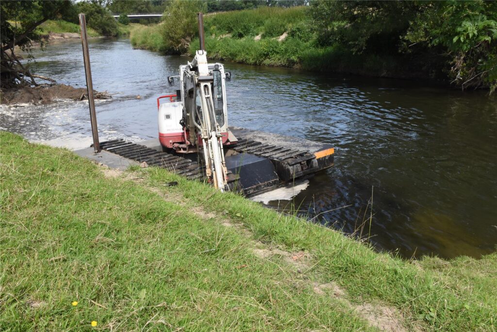 Ein Schwimmbagger gräbt auf der Lippe am Ufer.