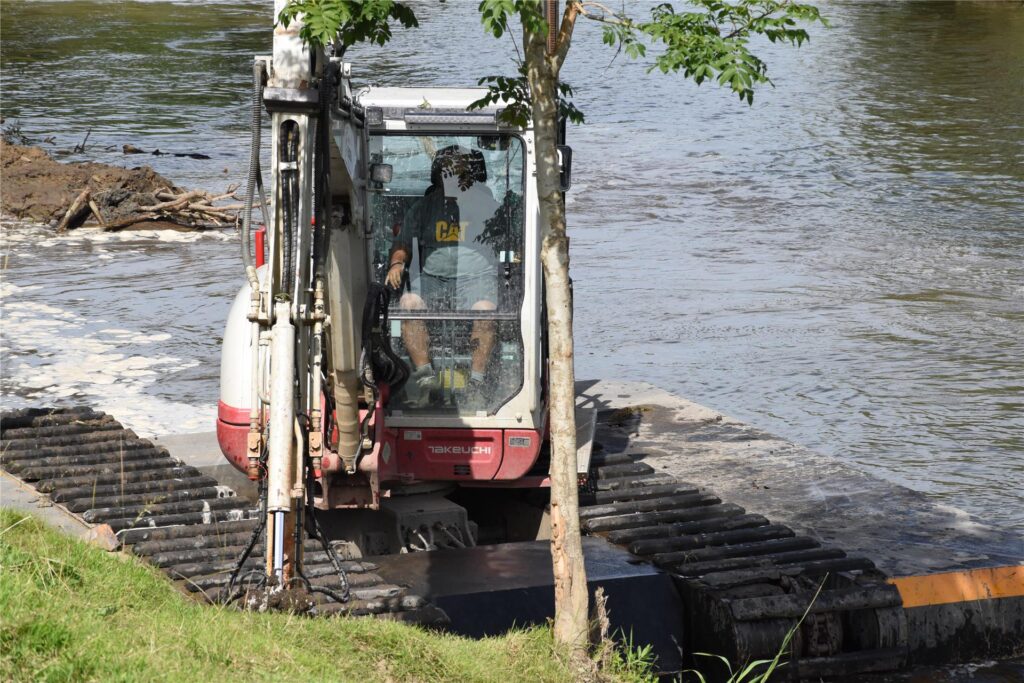 Ein Schwimmbagger gräbt auf der Lippe am Ufer.