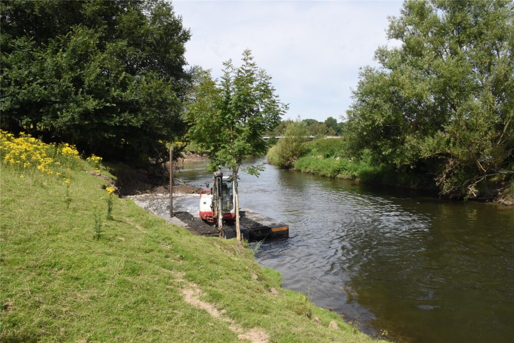 Ein Schwimmbagger gräbt auf der Lippe am Ufer.