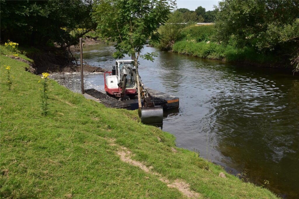 Ein Schwimmbagger gräbt auf der Lippe am Ufer.