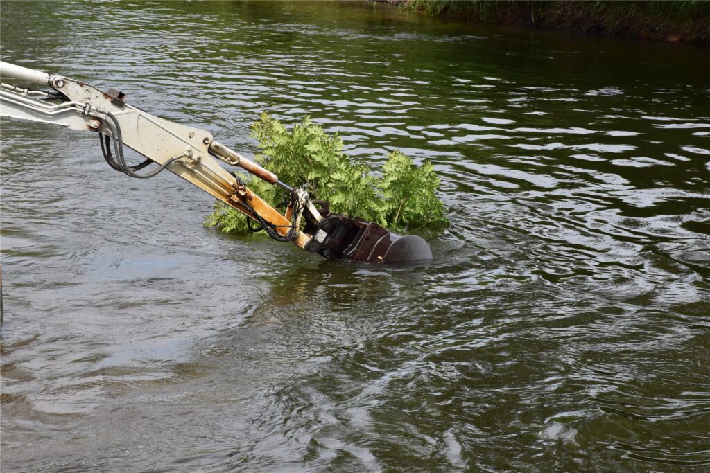 Ein Schwimmbagger gräbt auf der Lippe am Ufer.