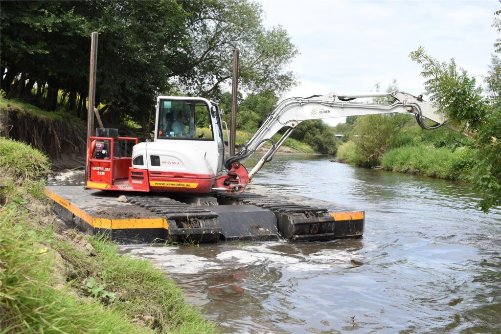 Ein Schwimmbagger gräbt auf der Lippe am Ufer.