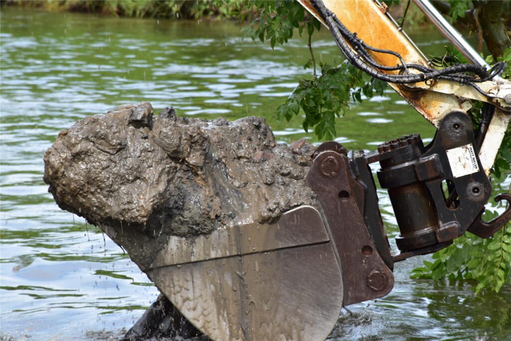 Ein Schwimmbagger gräbt auf der Lippe am Ufer.