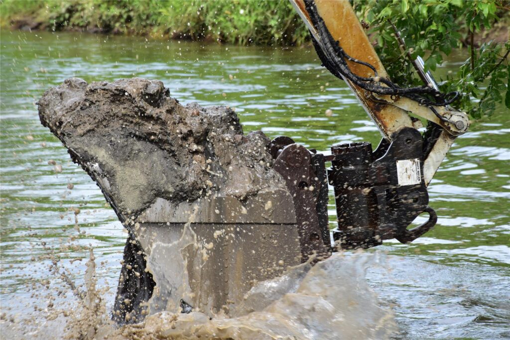 Ein Schwimmbagger gräbt auf der Lippe am Ufer.