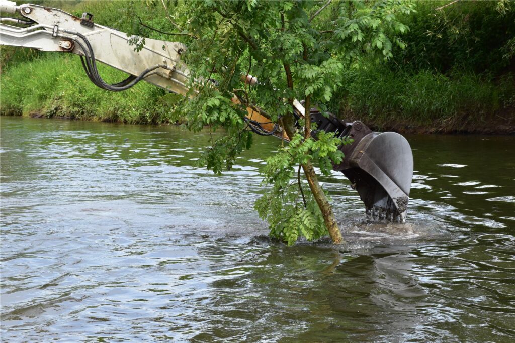 Ein Schwimmbagger gräbt auf der Lippe am Ufer.