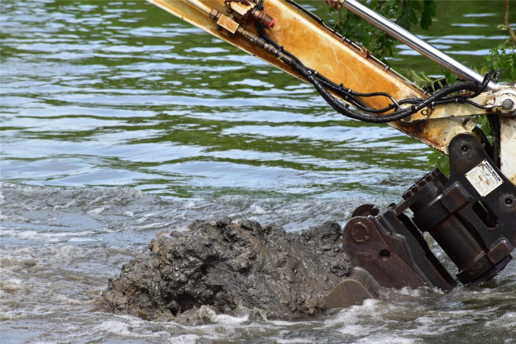 Ein Schwimmbagger gräbt auf der Lippe am Ufer.