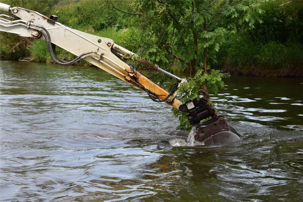 Ein Schwimmbagger gräbt auf der Lippe am Ufer.