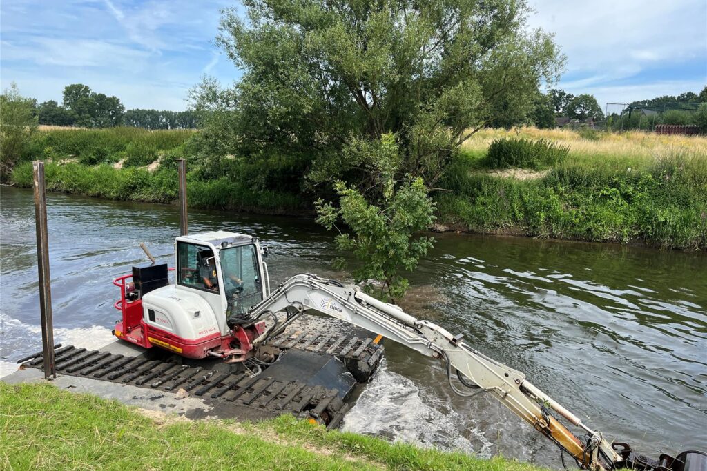 Ein Schwimmbagger gräbt auf der Lippe am Ufer.