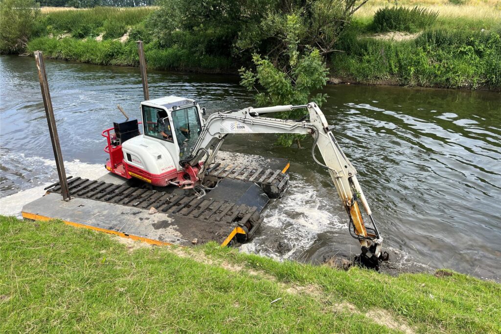 Ein Schwimmbagger gräbt auf der Lippe am Ufer.