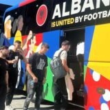 Mehrere Fußballspieler besteigen einen Bus mit der Aufschrift „Albany is united by football“ (Albanien wird durch den Fußball vereint).
