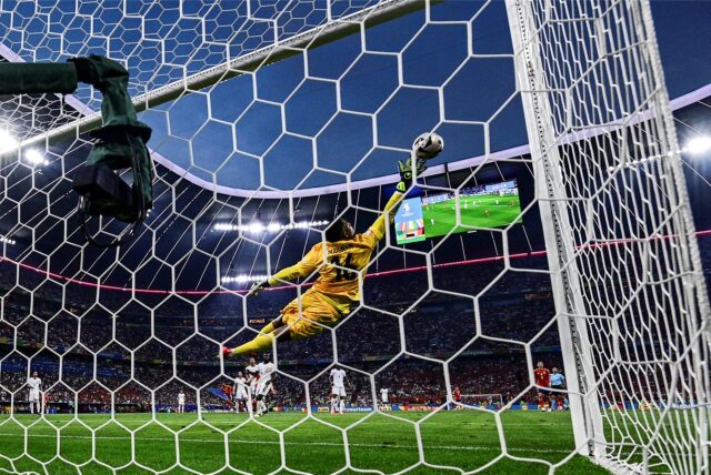 Der französische Keeper Mike Maignan liegt quer in der Luft. Der Ball fliegt an ihm vorbei ins Tor.