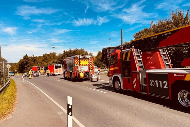 Einsatzfahrzeuge stehen auf einer Straße, im Hintergrund sind zwei beschädigte PKW zu sehen.