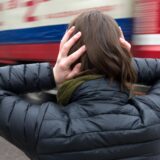 Eine Frau hält sich die Ohren zu, ein Schwerlaster fährt vorbei.