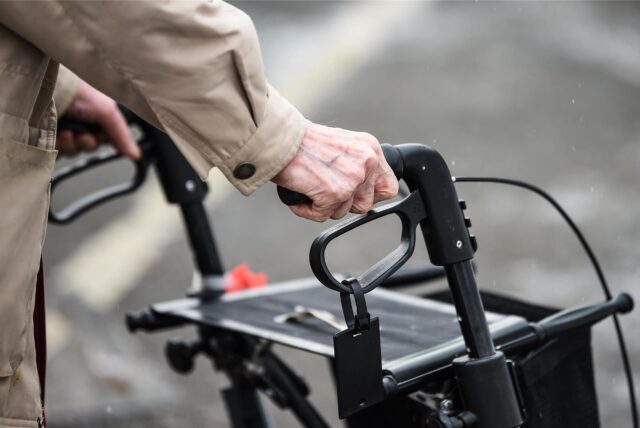 Eine alte Person ist mit einem Rollator unterwegs.