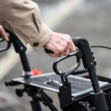 Eine alte Person ist mit einem Rollator unterwegs.