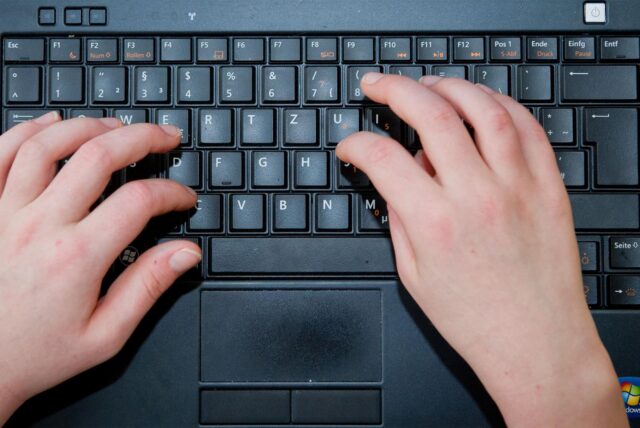 Zwei Hände tippen auf einer Tastatur.