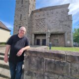 Ein Mann steht vor einer Kirche.