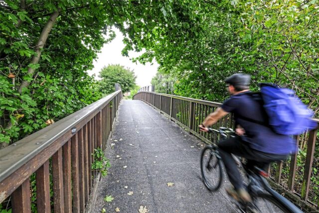 Ein Radfahrer fährt über eine Holzbrücke