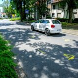 Ein weißes Auto fährt auf der Westfalenstraße in Richtung Kreisverkehr. Auf Höhe des Autos sind gelbe Markierungen auf der Fahrbahn.