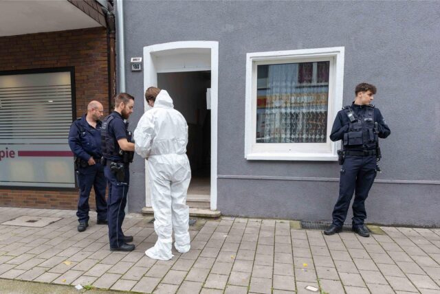 Gelsenkirchen: Mehrere Beamte stehen vor der Haustür des Mehrfamilienhauses, in dem die Frau tödlich verletzt worden ist.
