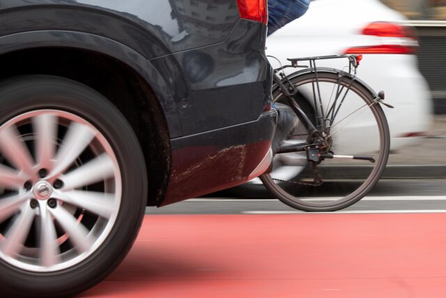 Ein Fahrradfahrer fährt zwischen zwei Autos her.