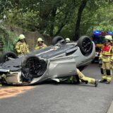 Nach einem schweren Unfall liegt ein Auto auf dem Dach. Einsatzkräfte der Feuerwehr stehen um das Auto herum.