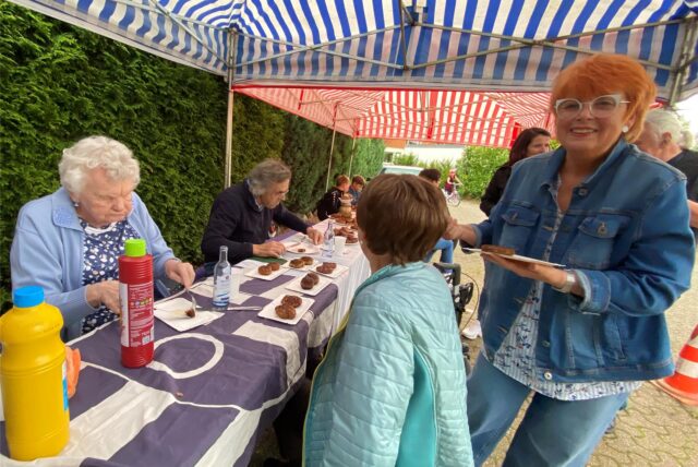 Menschen sitzen um einen Tisch mit Frikadellen drauf herum.