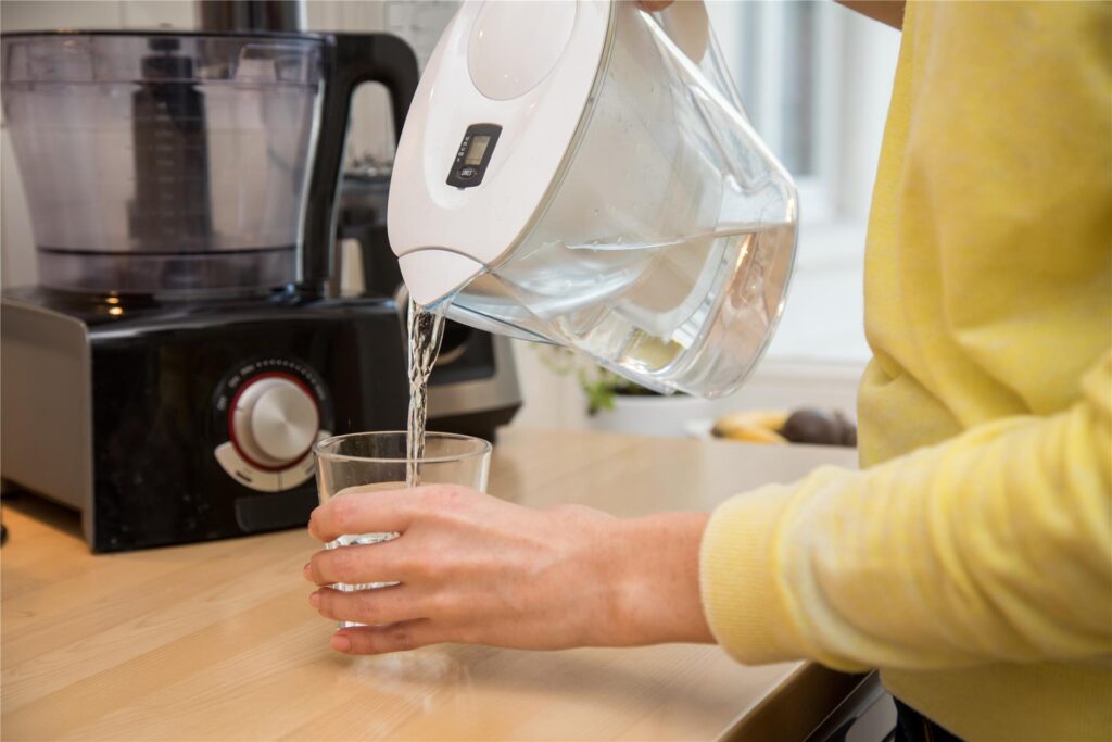 Eine Frau gießt gefiltertes Wasser in ein Glas. Eine Frau gießt gefiltertes Wasser in ein Glas.