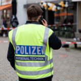 Ein Polizist tragt eine gelbe Warnweste mit dem Aufdruck „Polizei Kriminaltechnik“ und telefoniert.
