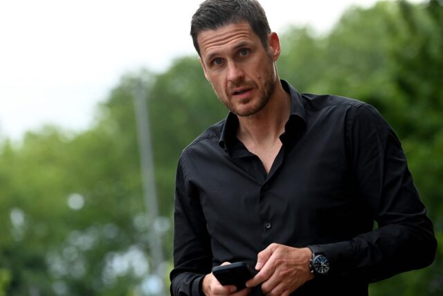Sebastian kehl hält sein Handy in der Hand.