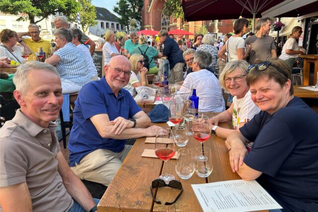 Männer und Frauen mit Weingläsern an einem Tisch