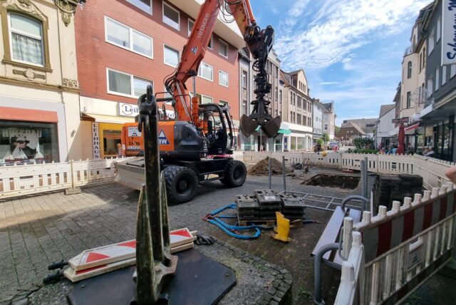 Ein Bagger steht in einer abgesperrten Baustelle.