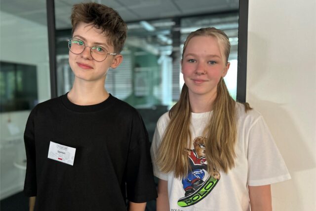 Ein Junge und ein Mädchen, die vor einem Fenster stehen.